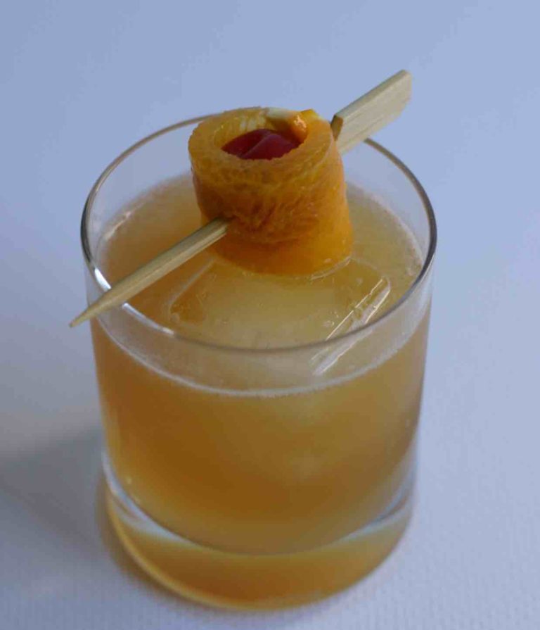 Un amaretto sour dans un verre rocks garni d'une cersie